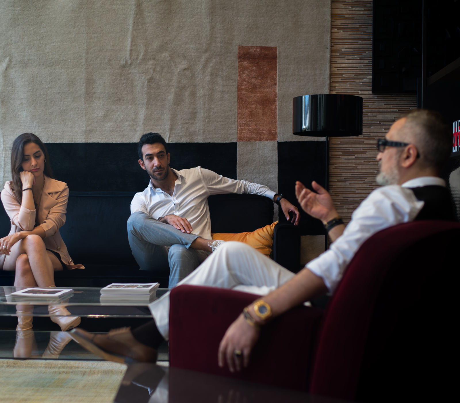 Three adults engaged in a thoughtful therapy session in a stylish Genoa interior.